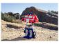 Ein Optimus Prime Spielzeug steht auf felsigem, sandigem Gelände unter klarem Himmel.