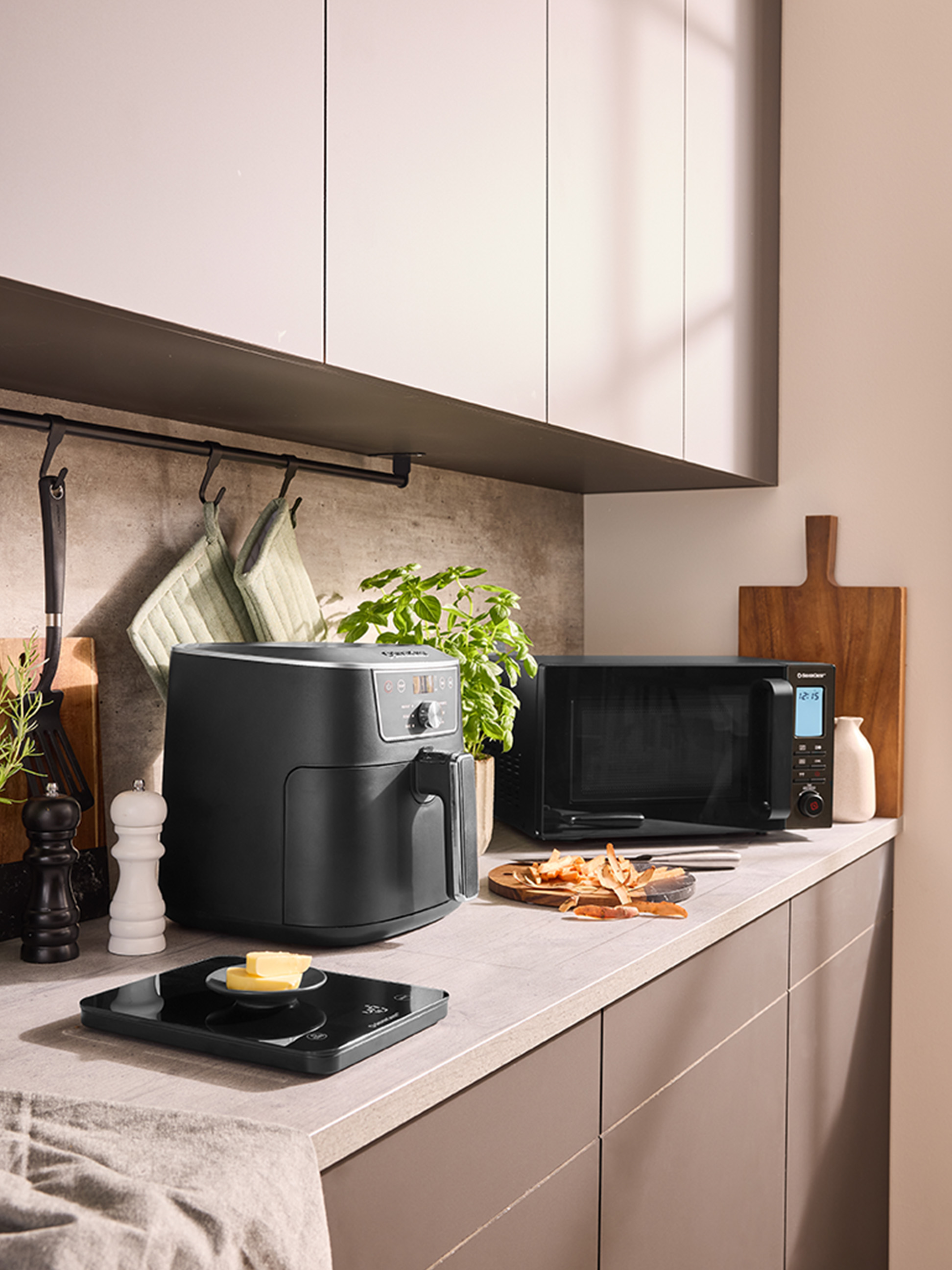 Eine Heißluftfritteuse und eine Mikrowelle auf einer modernen Küchenarbeitsplatte.