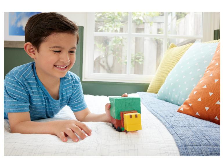 Lächelnder Junge spielt mit grünem und gelbem Spielzeug auf einem Bett.