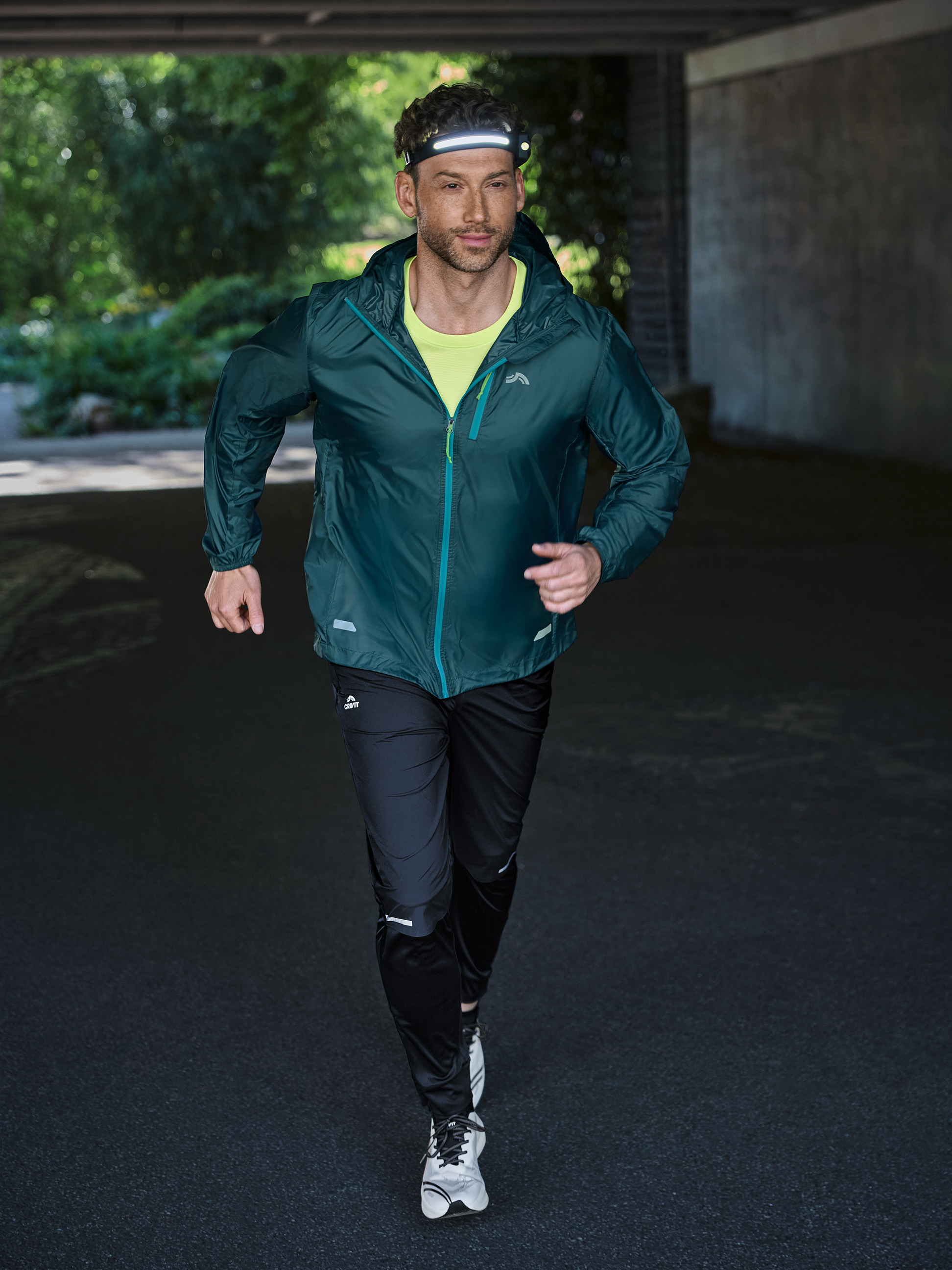 Mann läuft in Sportkleidung und Stirnlampe durch einen Tunnel