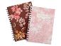 Zwei Spiralnotizbücher mit Blumenmustern, eines braun, das andere rosa mit der Aufschrift „NOTEBOOK“.
