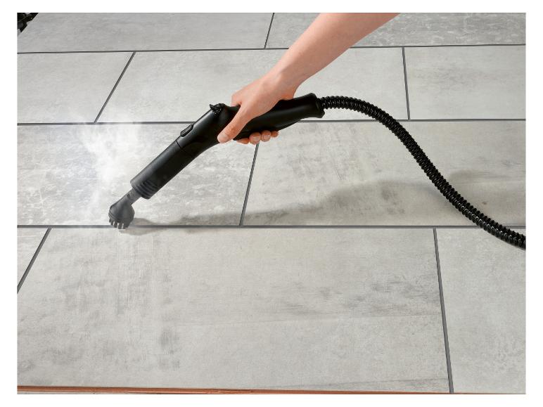 Hand hält Dampfreiniger, reinigt hellgraue Bodenfliesen mit Dampf