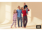 Lächelnde Familie in karierten Pyjamas, Vater und Tochter schauen zur Mutter, die ein lachendes Baby hält.
