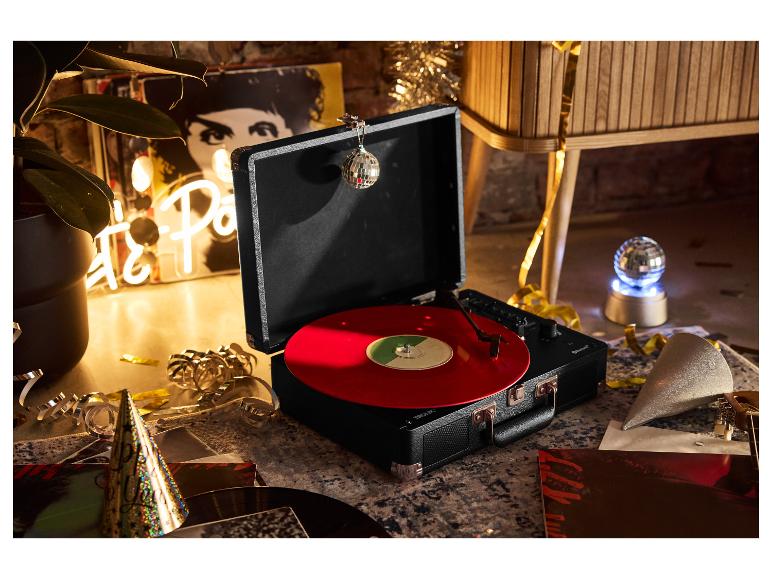 Plattenspieler mit roter Vinylplatte, festlich dekoriert mit Konfetti und Hüten.