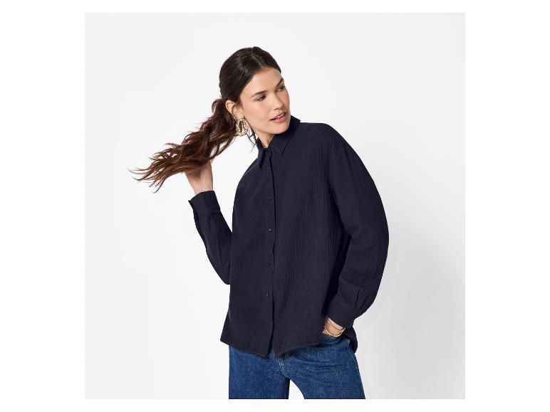 Frau in dunkelblauem Hemd und Jeans, hält ihre Haare.