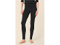 Frau in schwarzen Leggings und schwarzem Oberteil, barfuß stehend.