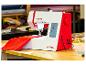 Rot-weiße Nähmaschine mit Stoff auf einem Holztisch in einer Werkstatt