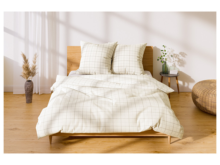 Ein Bett mit karierter Bettwäsche und Kissen in einem hellen Schlafzimmer.