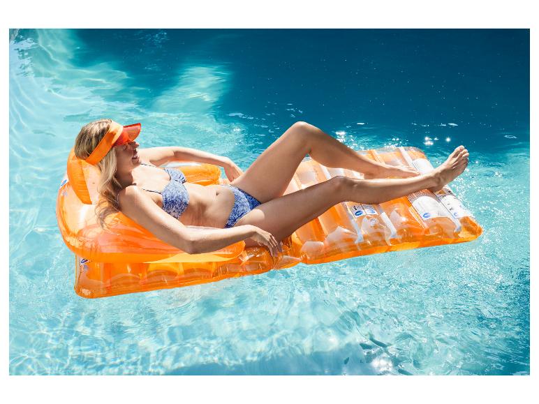 Frau im Bikini treibt auf einer orangefarbenen Luftmatratze im Pool.
