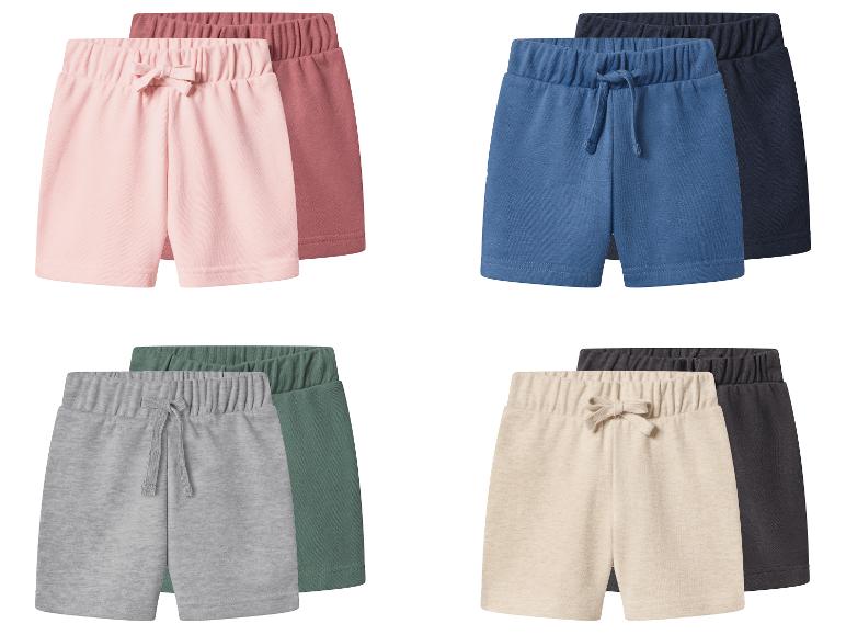 Vier Paar Kinder-Shorts in Rosa, Blau, Grau und Beige, jeweils mit einer dunkleren Komplementärfarbe.
