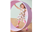 Mädchen in Kleid und Leggings mit Welpenmuster, rosa Turnschuhen, spielt mit einem lila Reifen.