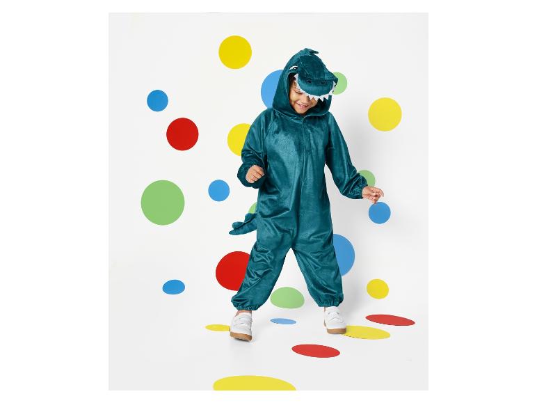 Ein Kind in einem grünen Dinosaurier-Overall läuft auf bunten Punkten.