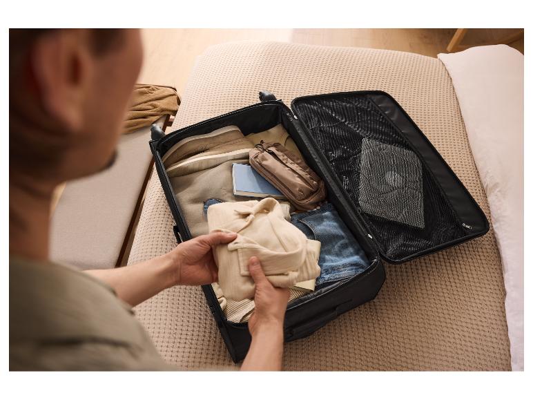 Ein Mann packt Kleidung in einen schwarzen ESMARA® Koffer auf dem Bett.