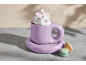 Lila Tasse mit heißer Schokolade, Sahne und bunten Marshmallows, dazu Macarons.