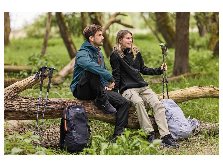 Zwei Wanderer sitzen auf einem Baumstamm, mit Wanderschuhen, Jacken und Rucksäcken.