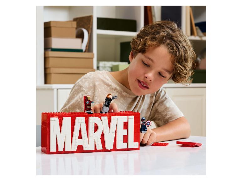 Junge spielt mit LEGO Marvel Logo und Iron Man, Black Widow und Captain America Minifiguren.
