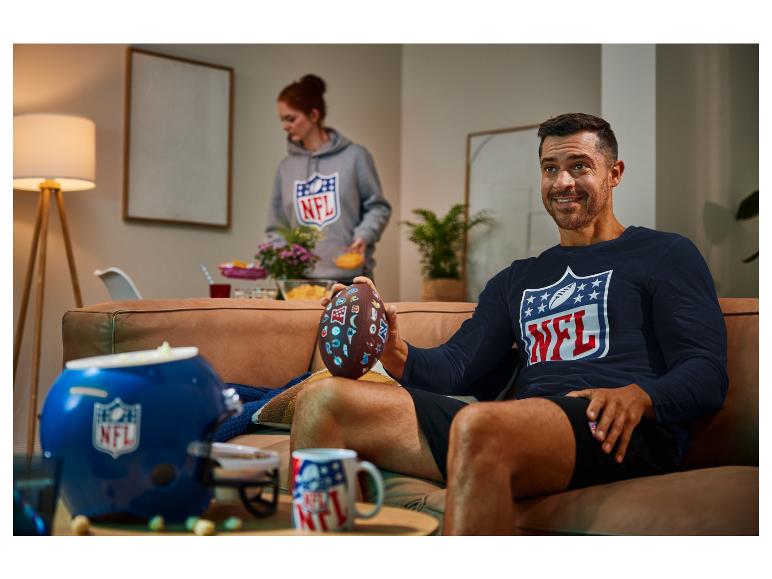 Ein Mann in einem NFL-Shirt mit einem NFL-Football in der Hand