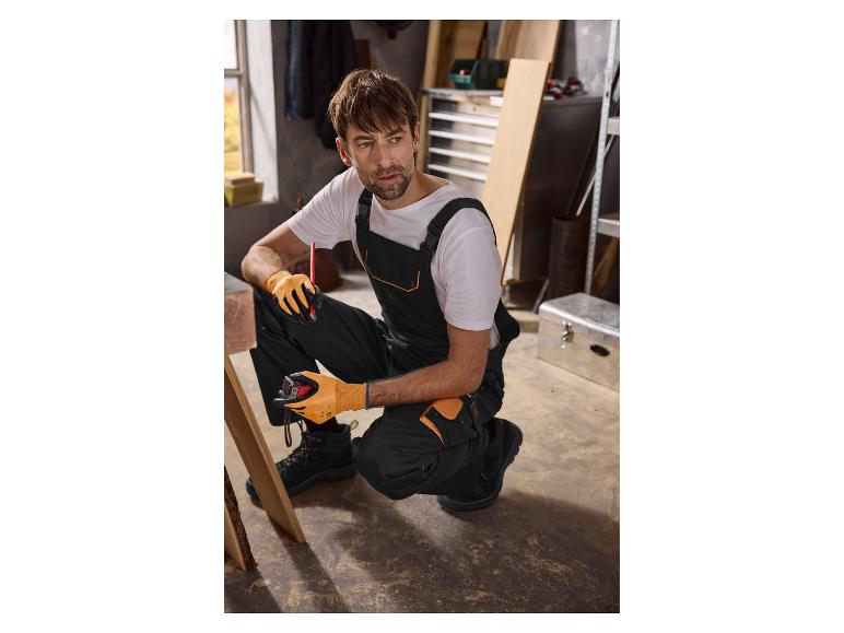 Mann in schwarzem Arbeitsanzug und orangefarbenen Handschuhen, mit Maßband und Bleistift.