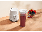 Weißer Standmixer mit einem Becher Smoothie und einer Schale mit Beeren.