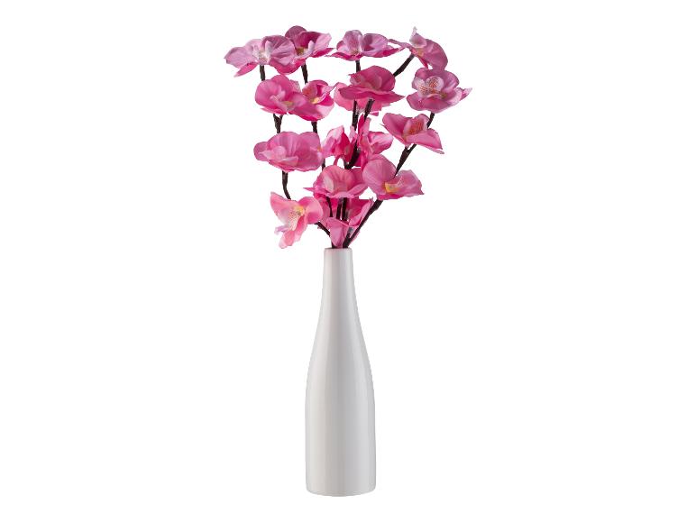 Eine weiße Vase mit rosa Kunstblumen.