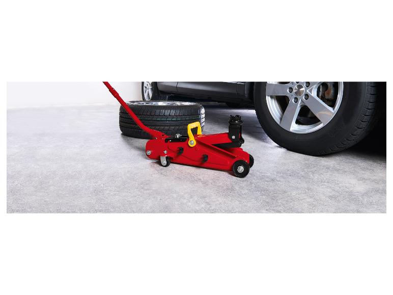 Roter Wagenheber und Reifen neben einem Auto in einer Garage.