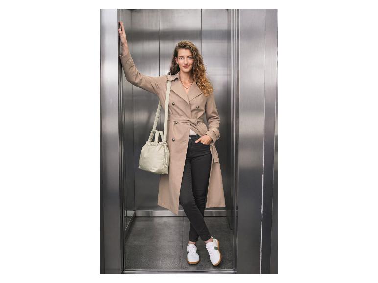 Frau in ESMARA® Jeans und Trenchcoat in einem Aufzug.