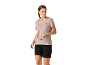 Frau in beigem Sport-T-Shirt und schwarzen Shorts, hält Sonnenbrille.