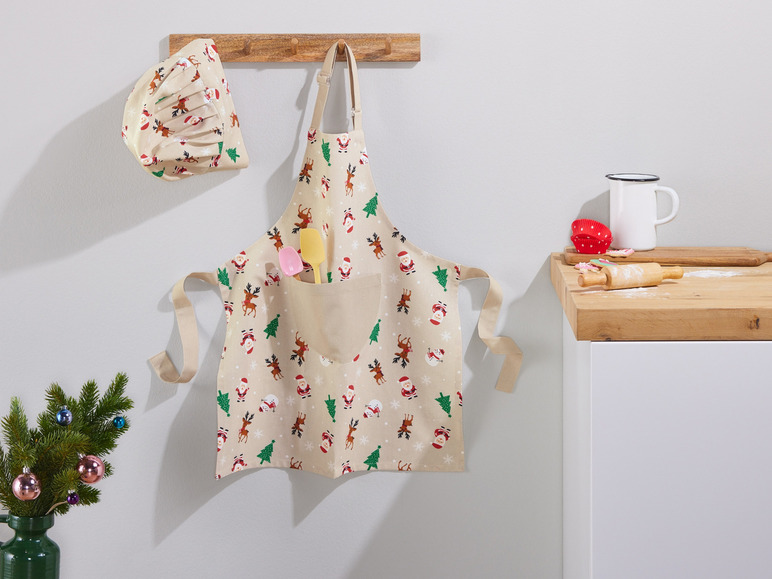 Eine Weihnachts-Schürze mit Rentieren und Weihnachtsmännern, eine passende Weihnachts-Kochmütze und Küchenutensilien.