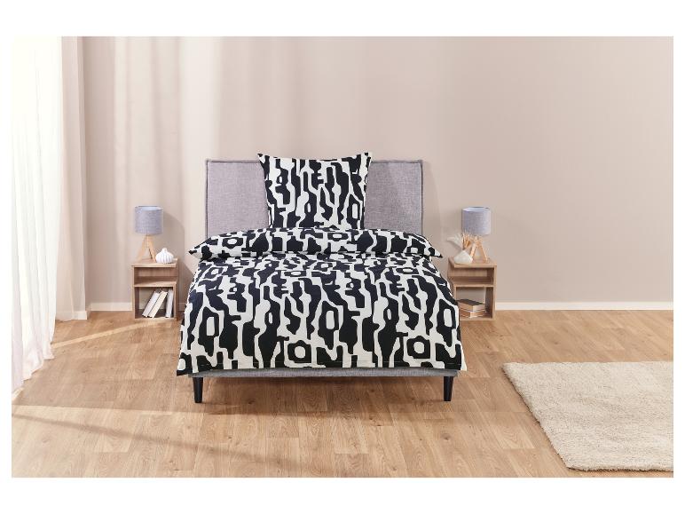 Ein Bett mit einer schwarz-weiß gestreiften Bettdecke und einem passenden Kissen.