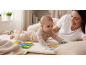 Mama und Baby spielen mit Pappbüchern auf einer Spielmatte.