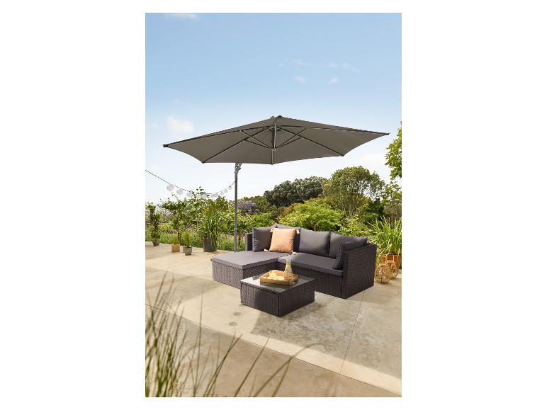 Outdoor-Rattan-Ecksofa-Set mit Kissen, Glastisch und großem grauem Sonnenschirm.