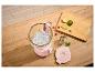 Rosa Mixer mit Eis, Limetten, Himbeeren und Minze auf einer Holztheke.