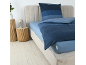 Schlafzimmer mit blau gestreifter Bettwäsche, hellblauem Spannbettlaken und zwei Holznebentischen.