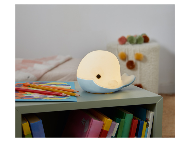 Eine blaue Wal-Nachttischlampe auf einem grünen Nachttisch.