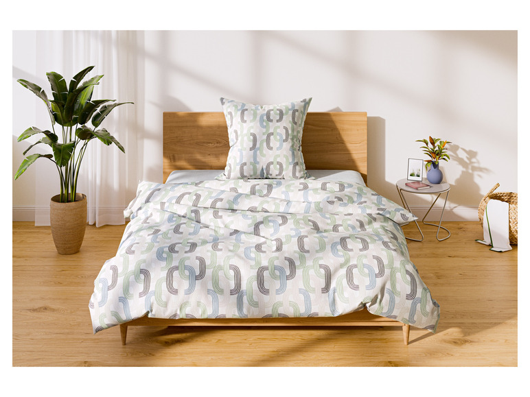 Ein Bett mit einer grünen und blauen Bettwäsche mit geometrischem Muster.