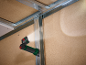 Magnetische Arbeitsleuchte beleuchtet eine Wand mit Metallständern und Holzplatten.