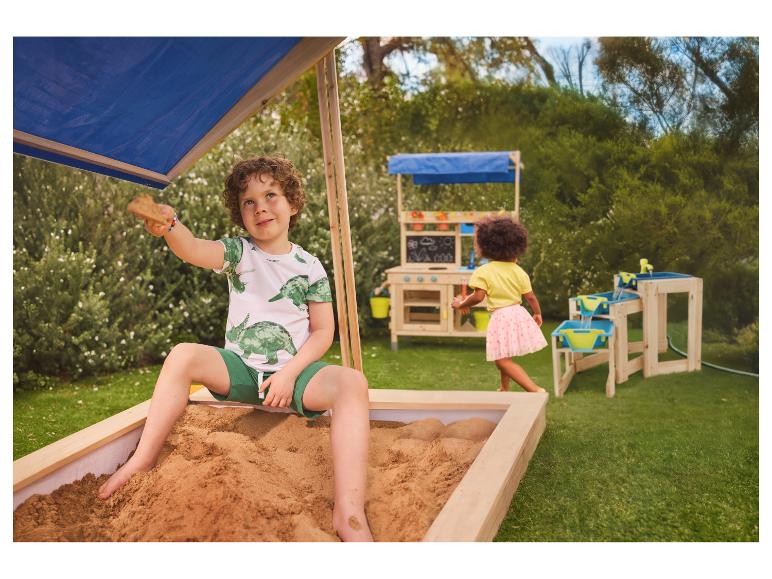 Kinder spielen in einem Sandkasten und mit Holz-Outdoor-Spielzeug im Garten.