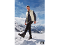 Mann in Steppweste und Pullover, Hose und Wanderstiefeln im Schnee.