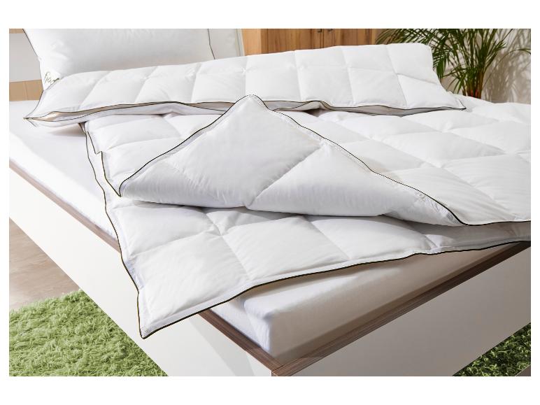 Weiße Bettdecke und Kissen mit dunklem Rand auf einem Bett mit grünem Teppich