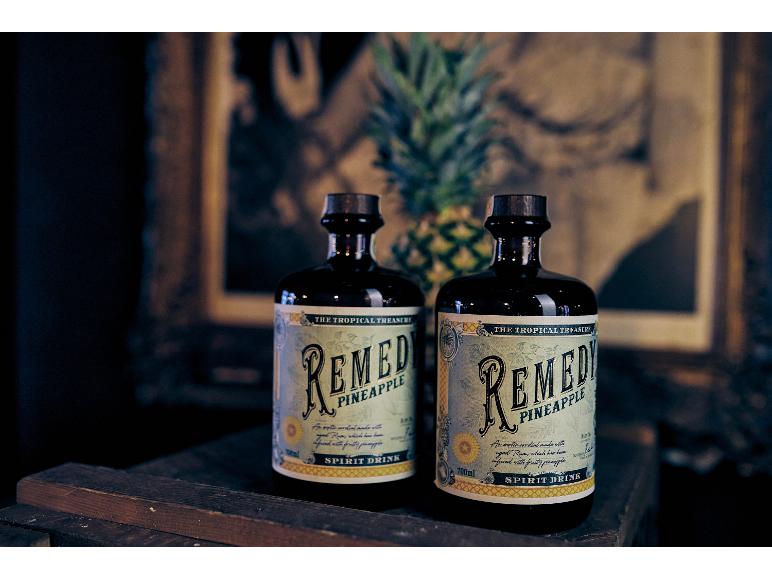 Zwei Ananas-Spirituosenflaschen, mit einer Ananas und gerahmter Kunst im Hintergrund.