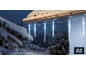 LED-Lichterkette in Eiszapfenform an einer verschneiten Dachrinne.