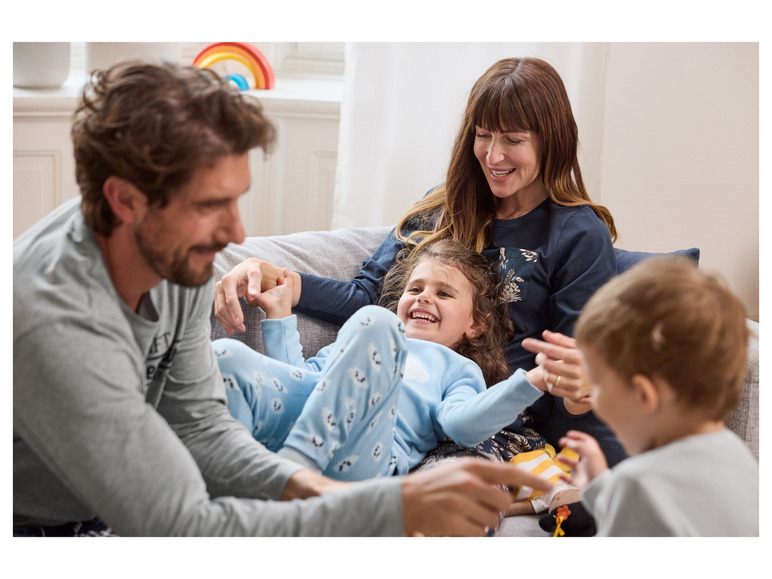 Eine Familie in bequemen Pyjamas entspannt zusammen auf dem Sofa.