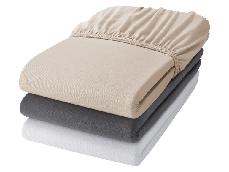 Gestapelte Spannbettlaken in Beige, Grau und Weiß.