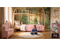 Mädchen liest in einem Wald-Kinderzimmer mit Hausbett, rosa Bettwäsche und Stauraum.