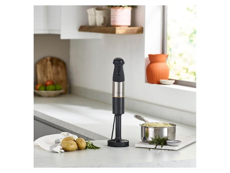 Stabmixer in einer Küche mit Kartoffelpüree, Kartoffeln und Kräutern.