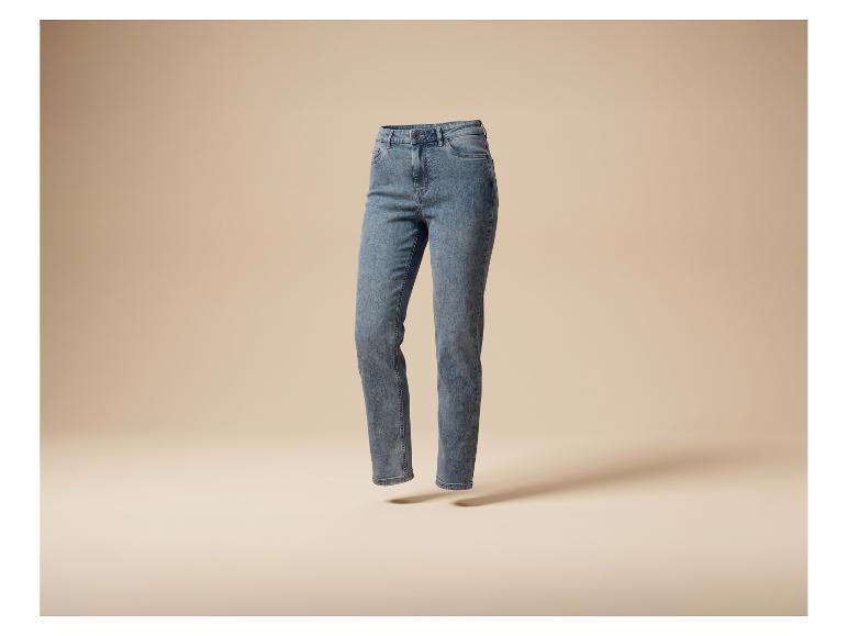 Blaue, ausgewaschene Damenjeans, schwebend vor beigem Hintergrund.