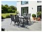 Garten-Essgruppe mit vier Stühlen und einem Tisch auf einer Terrasse, umgeben von Grün.