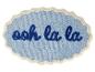 Blauer Badteppich mit dunkelblauem Schriftzug „ooh la la“ und gewelltem Rand.