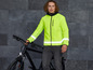 Mann mit einer reflektierenden Jacke und einem schwarzen Fahrrad.