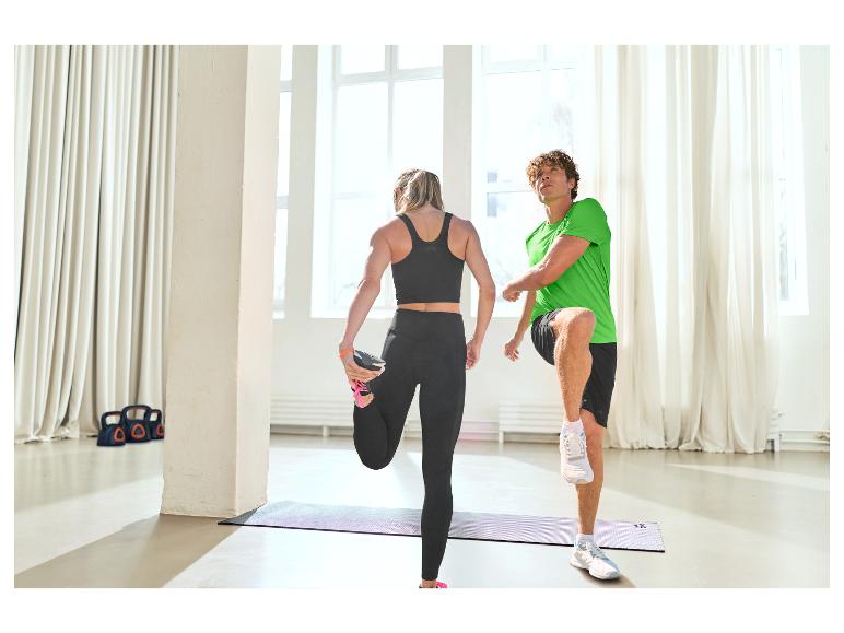 Zwei Personen dehnen sich auf Yogamatten in Sportkleidung.